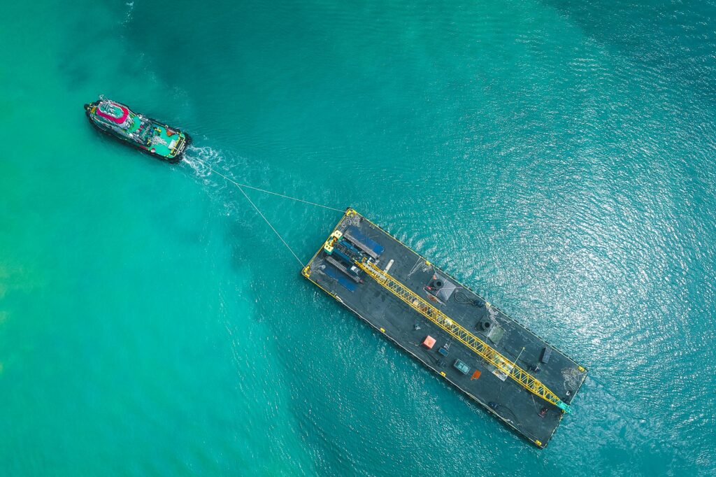 Aerial view of modern vessel floating on rippling blue seawater and pulling big platform